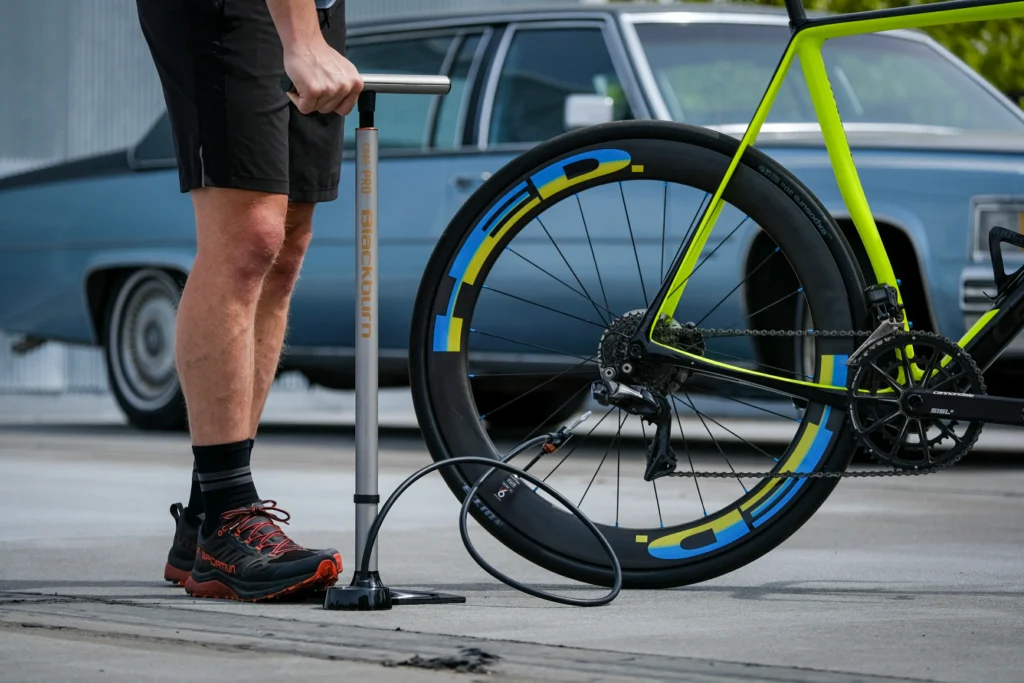 Cyclist checking road bike tire pressure with digital gauge representing best bike tire pressure calculator in 2026.