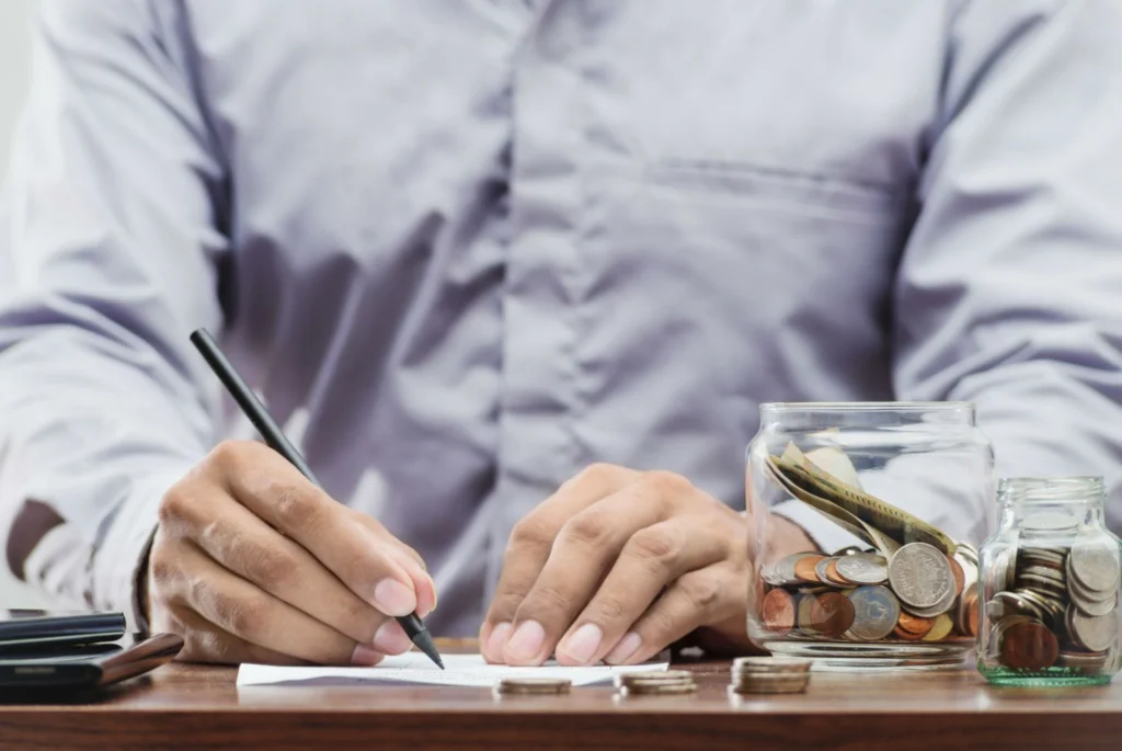 Person deciding between CD and savings account using calculator and notes on a clean desk.